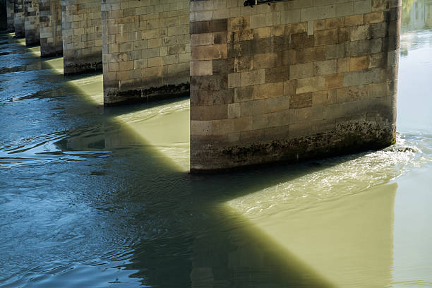 assau, Bavaria, Germany: sunlight and shadows of a bridge on pillars crossing the fast flowing Inn river