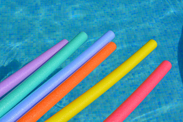 istock Multi-coloured pool noodles floating on swimming pool 2238758180