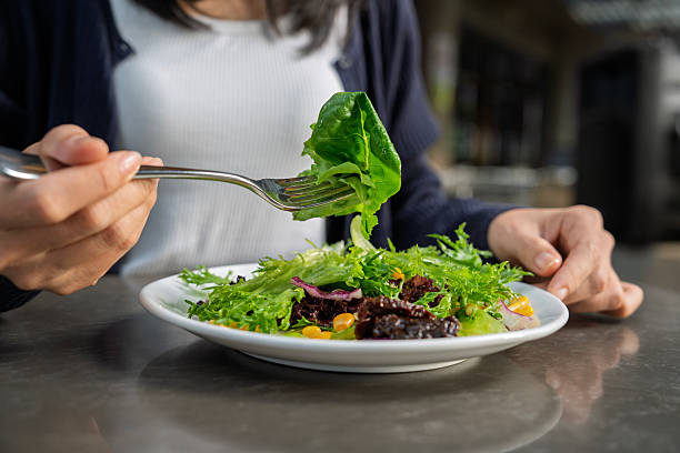A woman eating fresh salad with corn and lettuce