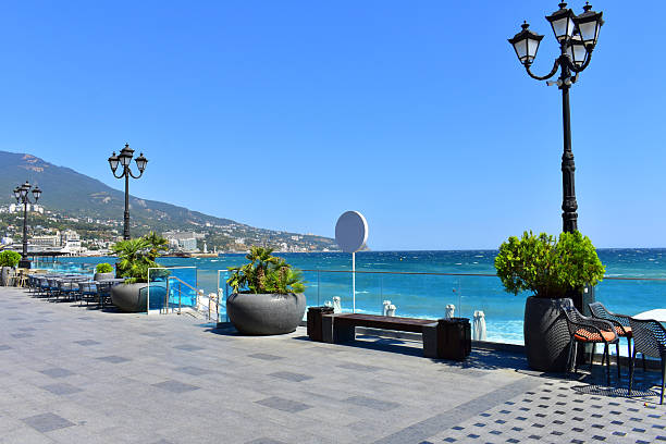 Summer view of the Yalta embankment with benches, pots with plants, lanterns, sea and mountains, Crimea, Yalta, August 2025