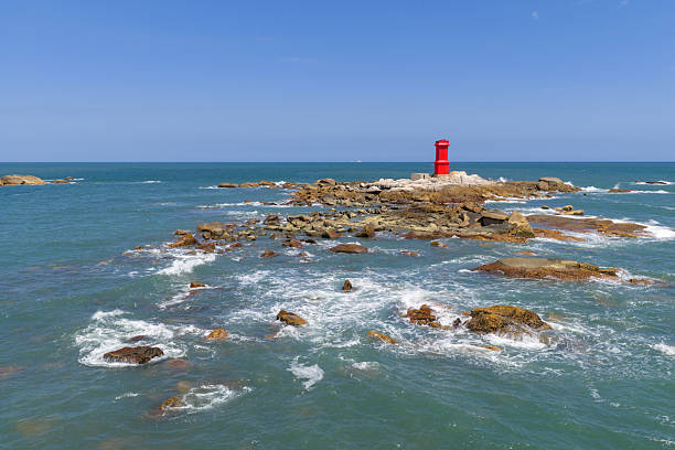 China's Fujian Province, waves crashing against the rocks, red lighthouse on the rocks