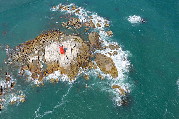 China's Fujian Province, waves crashing against the rocks, red lighthouse on the rocks