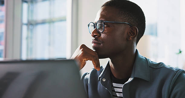istock Thinking, employee and man with laptop, office or plan for UX design on website, creative or online. Reflection, graphic designer and black person with solution for project, serious and research 2238768138