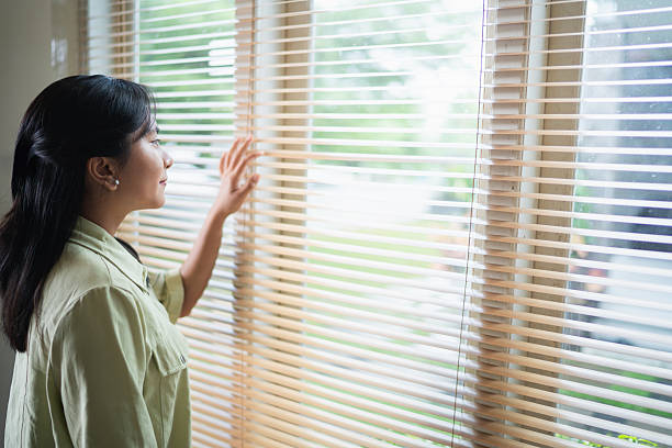 istock Woman staring outside through window blinds in natural light 2238771498