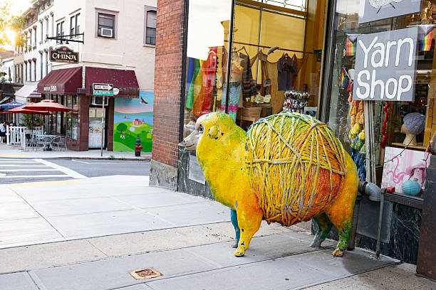 July 17th, 2025: Tarrytown, New York, United States - On the Main Street sidewalk a multi colored, larger than life sheep with a skein for a stomach is displayed outside of a yarn shop.