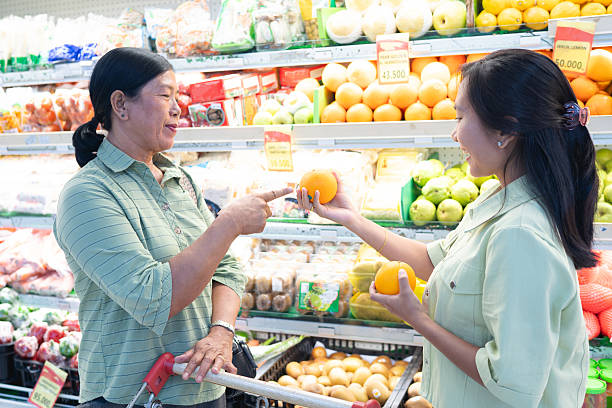 Smiling women choosing oranges while grocery shopping at supermarket