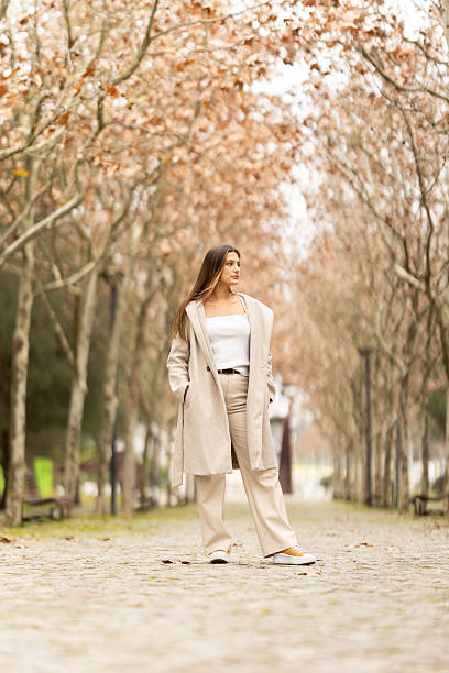 istock Stylish woman walking pensive through tree-lined avenue 2238776525