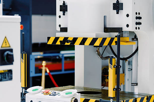 A female engineer in red overalls and hard hat operates factory machinery with focused precision. Captures industrial expertise and dedication in a manufacturing environment.