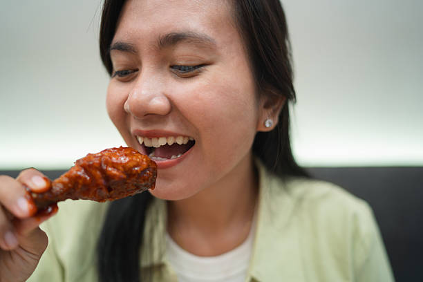 istock Woman taking a bite of spicy fried chicken drumstick 2238778994