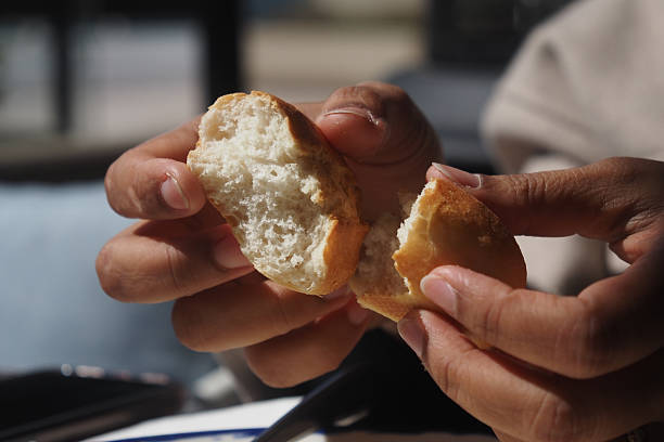 istock Hands breaking apart freshly baked bread in a sunny cafe 2238788052