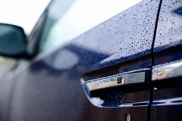 Raindrops on blue vehicle door handle and side view mirror