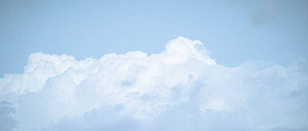 Vintage grainy film captures beautiful clouds against a clear blue sky.