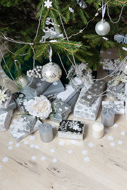 istock Modern and chic steel-tone gift boxes arranged beneath a beautifully decorated Christmas tree, complemented by candlelight and festive accents for a serene holiday mood 2238792529