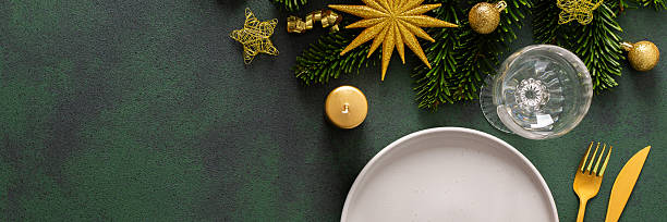 istock A Christmas table setting with an empty plate and cutlery on a green background. Spruse branches and golden tree decorations add elegance and festive cheer to the scene, banner 2238792564