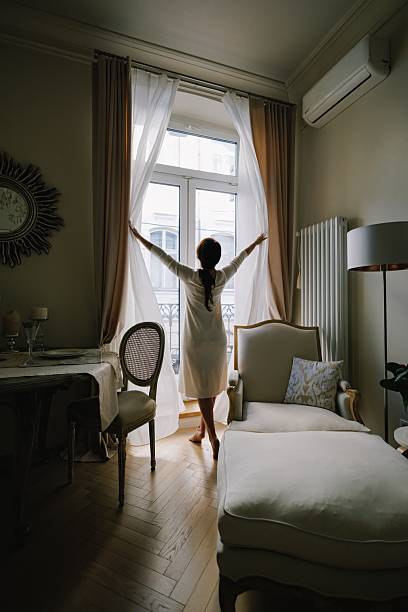 istock Woman opening curtains in morning light 2238798396