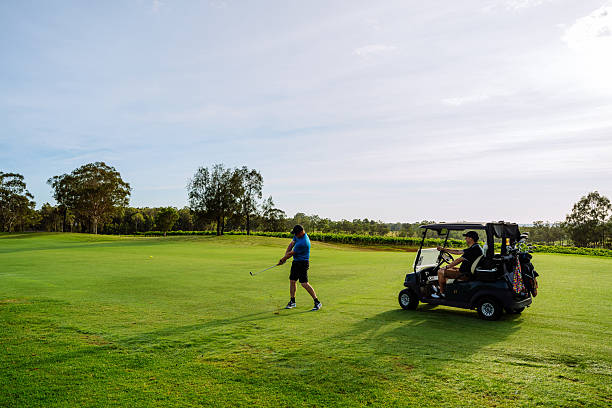 istock Man in golf clothing swinging on a lush green golf course surrounded by trees under a clear blue sky 2238804512