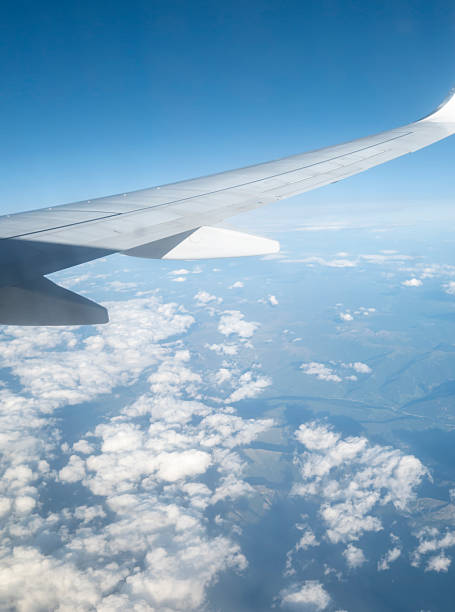 istock View from an airplane window featuring a wing against a clear blue sky and fluffy clouds. Perfect for travel and aviation themes during daytime. 2238804907