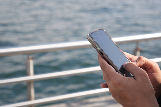 istock Person using smartphone by the water at a pier 2238806031