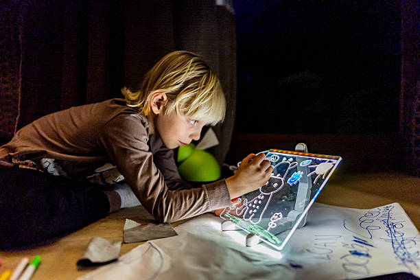 Boy drawing on LED light-up drawing board at home