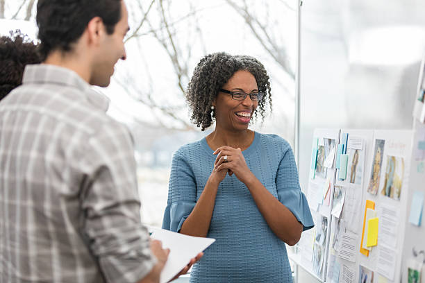 istock Two people collaborating and brainstorming ideas while looking at a presentation board with various notes and images. 2238815828