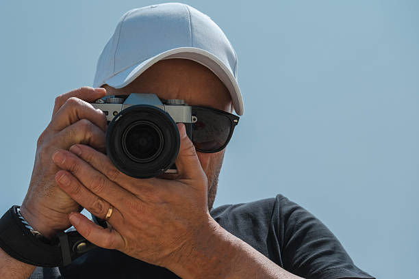 istock A man wearing a white hat and sunglasses is taking a picture with a reflex camera 2238822755