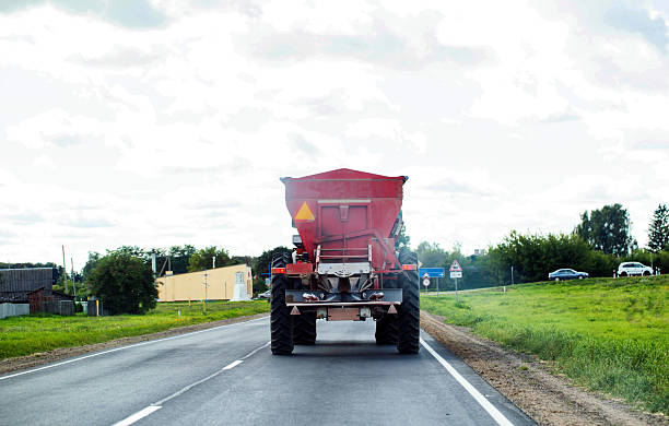 istock A tractor pulls a semi-trailer with a seed drill along a village road to apply fertilizers and minerals to a field. Copy space for text 2238825751