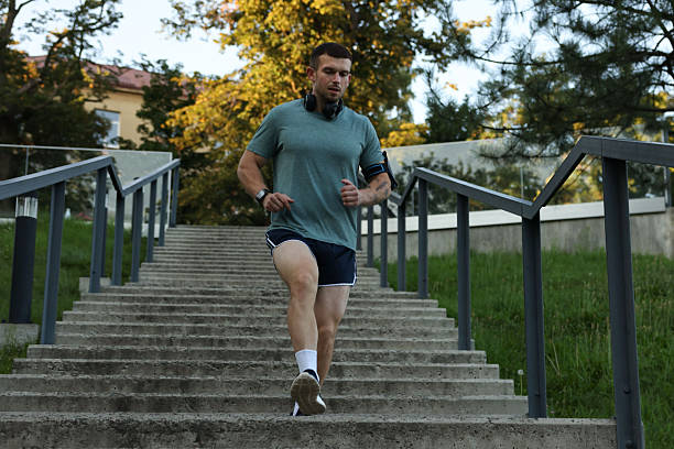 Athletic young man in sportswear running down stairs outdoors, low angle view