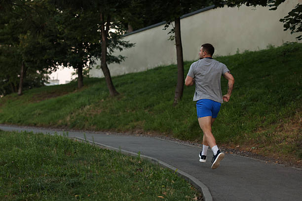 istock Athletic young man in sportswear running outdoors, back view. Space for text 2238828246