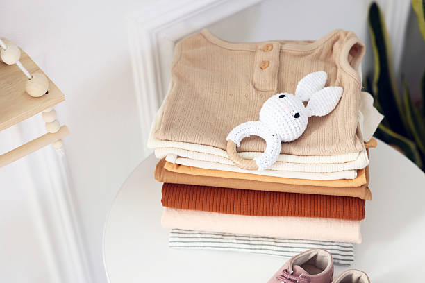 istock Stack of clean baby clothes and accessories on white table indoors 2238829132