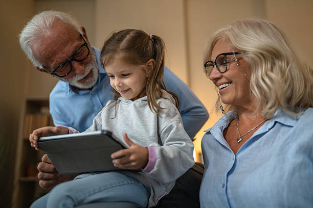 istock Grandchild using digital tablet with her grandparents at home 2238835420