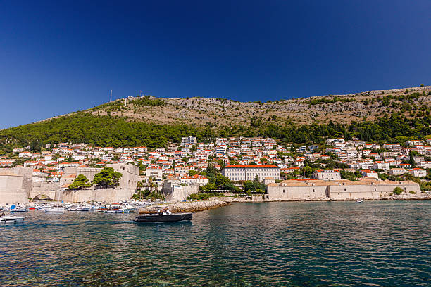 Dubrovnik, Croatia - September 13th 2025- A picturesque Dubrovnik along the Adriatic coast features charming homes on a hillside with clear blue water below.