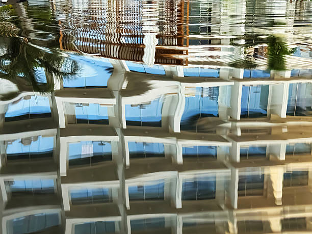 Reflections of a modern building in tranquil water create a serene view at a sunny resort.