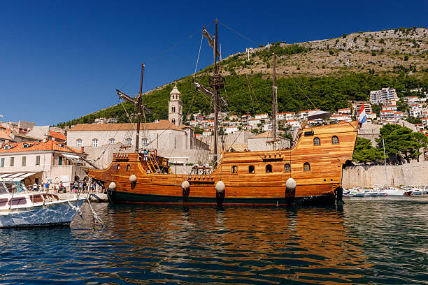 Elevated view depicting sailboats in the harbor and the architecture of the ancient old town of Dubrovnik, Croatia. Beyond is the deep blue water of the Adriatic Sea.
