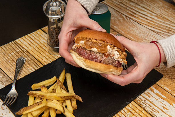 istock holding in two hands a beef burger with cream cheese, crispy and caramelized onions 2238847696
