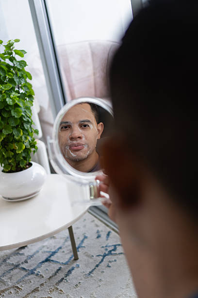 istock Man applying hydrating face mask looking in mirror 2238878768