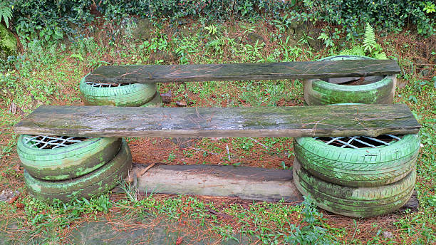 Rustic bench made from recycled tires and wooden planks in a garden setting.