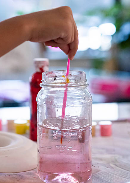 istock Child Rinsing Paintbrush in Water Jar During Art Project 2238880135