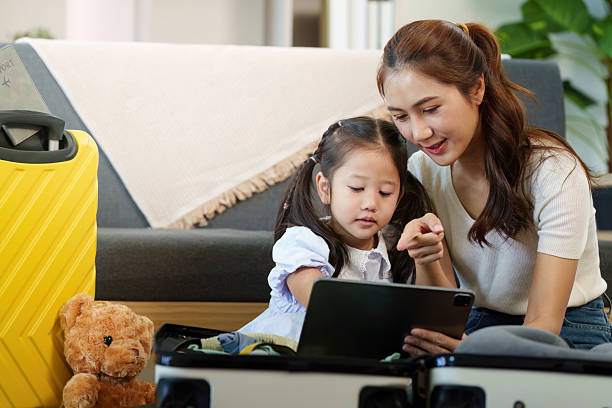 istock Travel Planning. Mother and daughter engaging with a tablet while packing. 2238884346