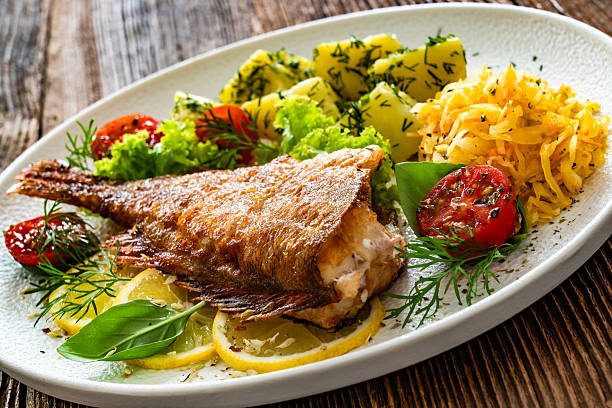 istock Fried atlantic redfish with boiled potatoes and sauerkraut on wooden table 2238885590