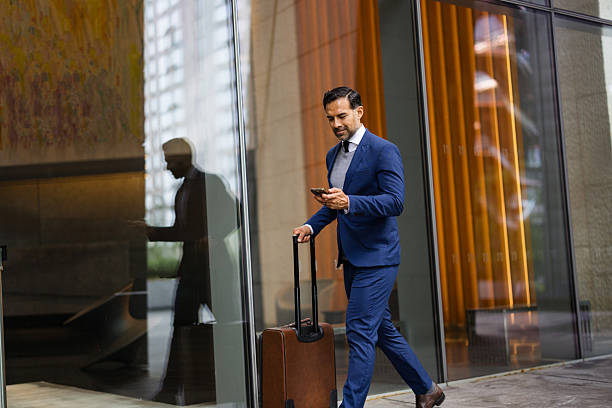 istock Businessman walking with suitcase and using smartphone 2238885949