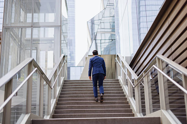 istock Businessman walking up stairs in modern office building 2238886026