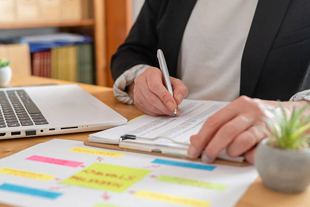 istock Businesswoman's hands take notes on a clipboard while reviewing financial reports, charts and marketing strategy beside a laptop on an office desk, focused on metrics and planning 2238892050