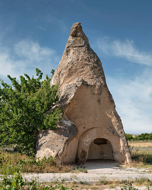 Pasabag Valley's iconic fairy chimney rock formation with ancient cave dwelling, Cappadocia, Turkey. Blue sky, green foliage