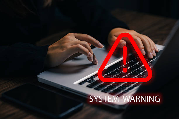 istock Cybersecurity system warning alert displayed on laptop with hands typing in the background. Concept of computer virus, malware attack, phishing scam, and cyber risk notification. 2238897653