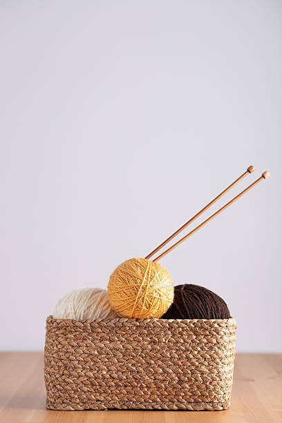 istock Yarn balls and knitting needles in wicker basket on table, vertical frame with light minimalist background. Copy space. Concept of knitting hobby and handmade creativity 2238898021