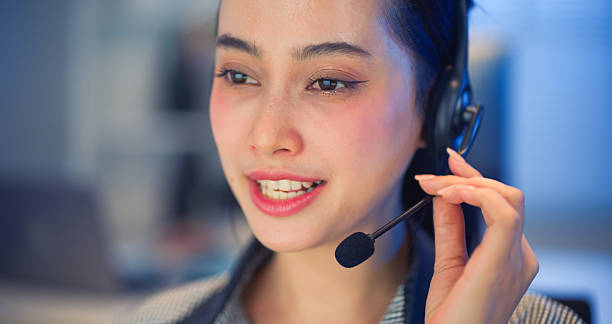 istock Asian woman with headset talking and smiling while working in call center office. 2238901321