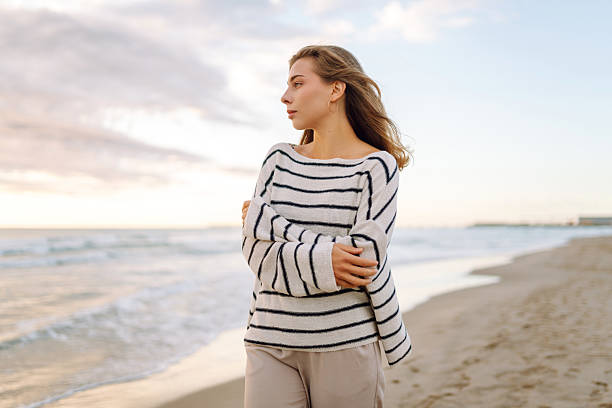 istock A young woman stands on a beach during sunset 2238912782