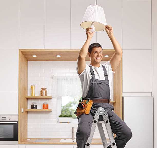 istock Repairman seated on a ladder changing a light bulb on a kitchen ceiling 2238913432