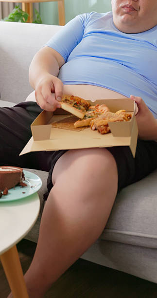istock obese man eating junk food at home 2238914227