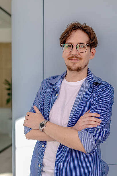 istock Young businessman smiles confidently while standing in a modern office environment 2238914617